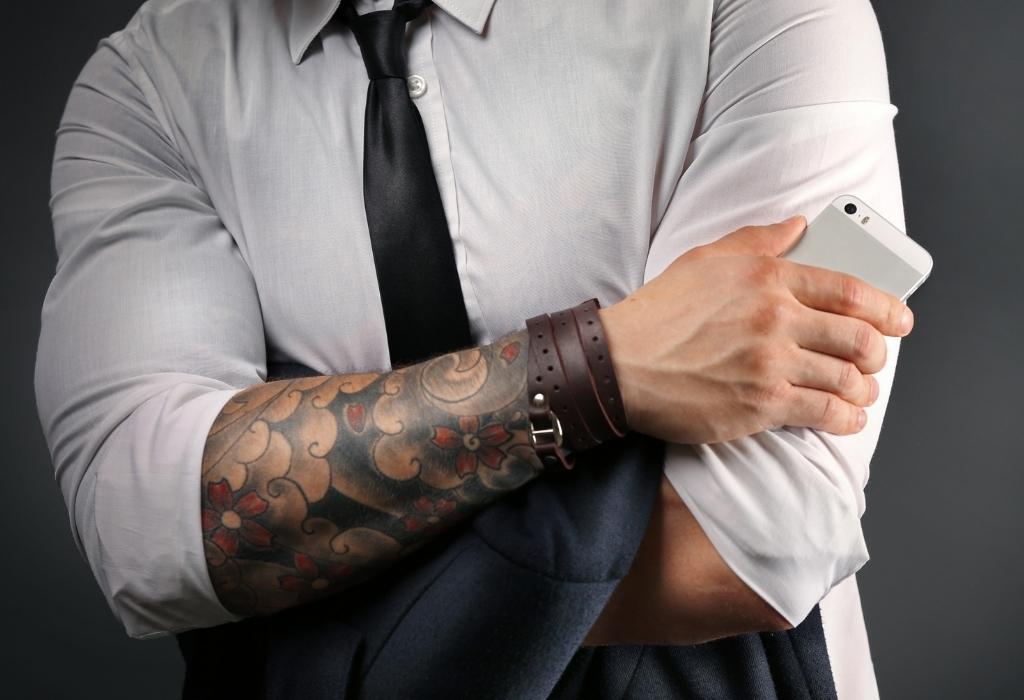 man in shirt and tie showing tattooed hand
