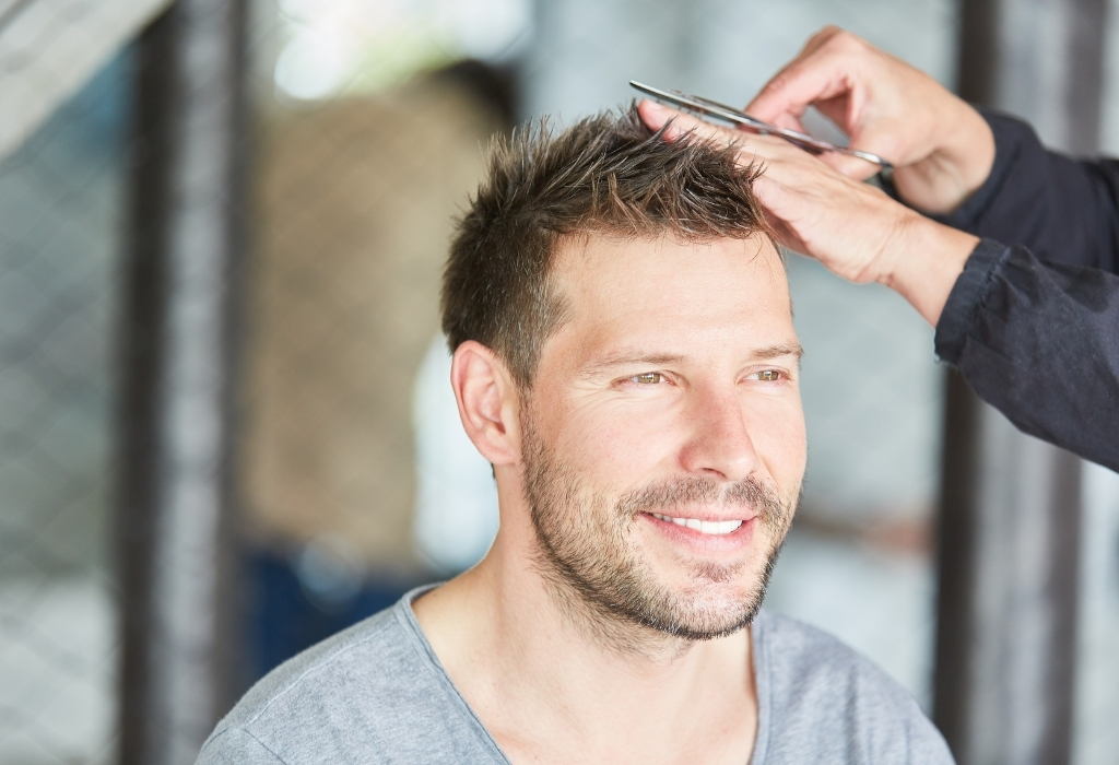 mann, der zu hause haare mit einer schere schneidet