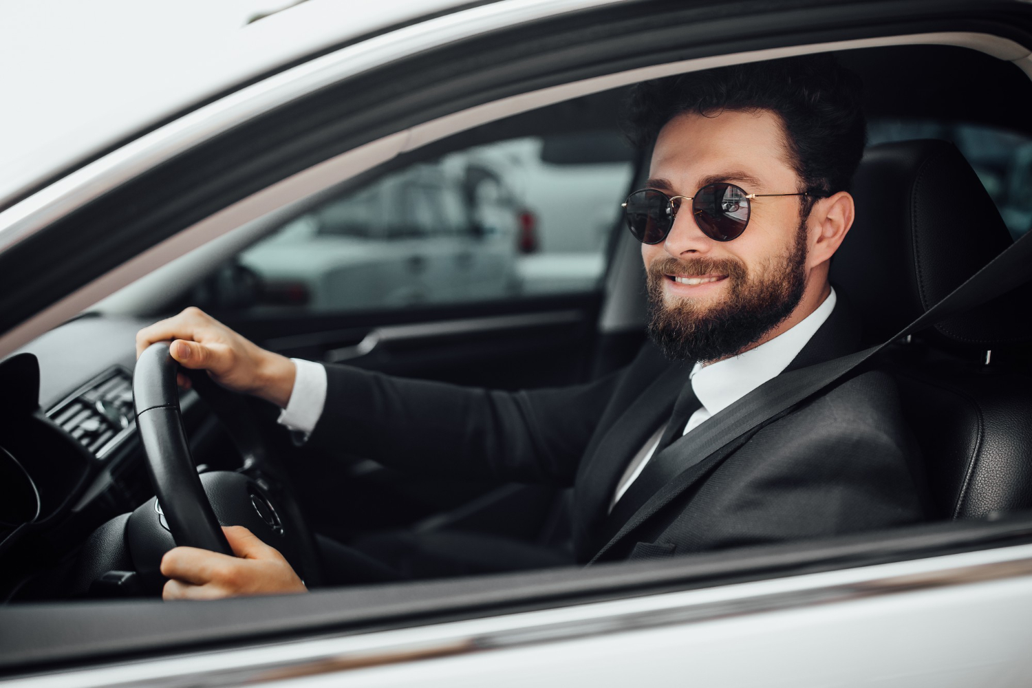 handsome-young-smiling-bearded-driver-full-suit-with-fastening-seat-belt-driving-new-white-car