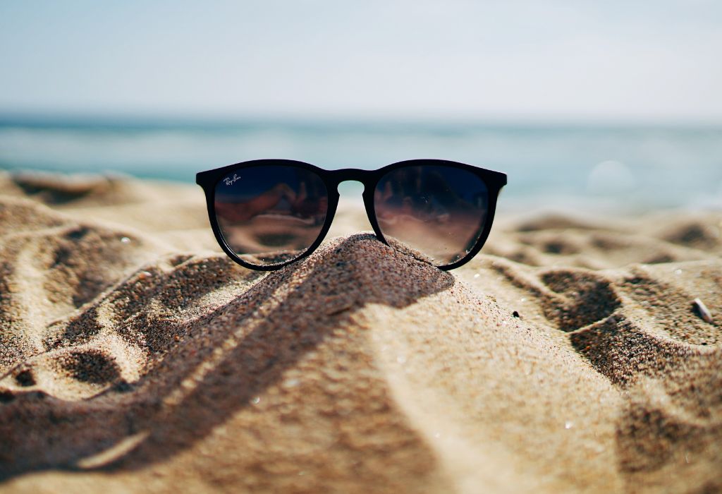 glasses protecting from sun laying on sand